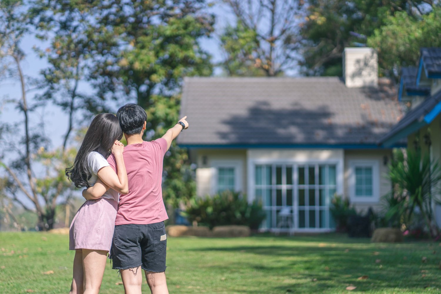young asian women pointing at a house planning to buy second hand house